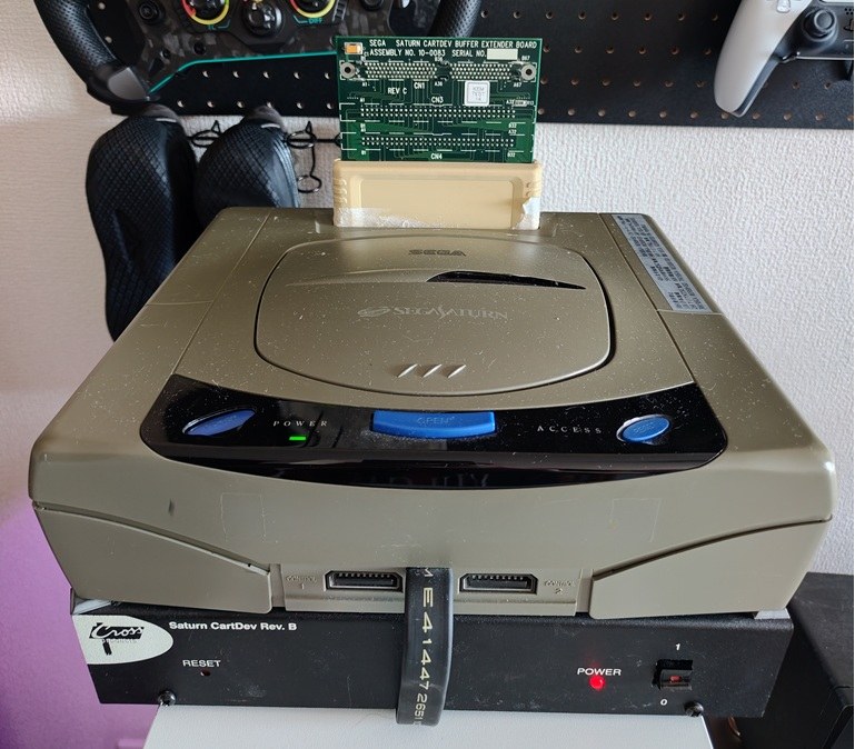 The CartDev board seated in the Saturn's cartridge slot, with the Saturn CartDev Rev. B unit underneath